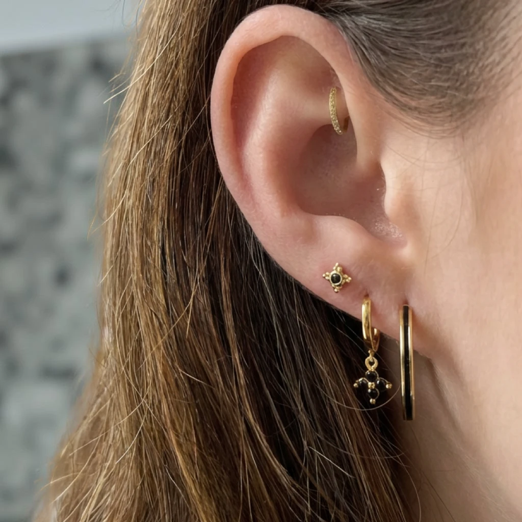 Gouden stud oorbel met sneeuwvlokdesign en zwarte details - vooraanzicht