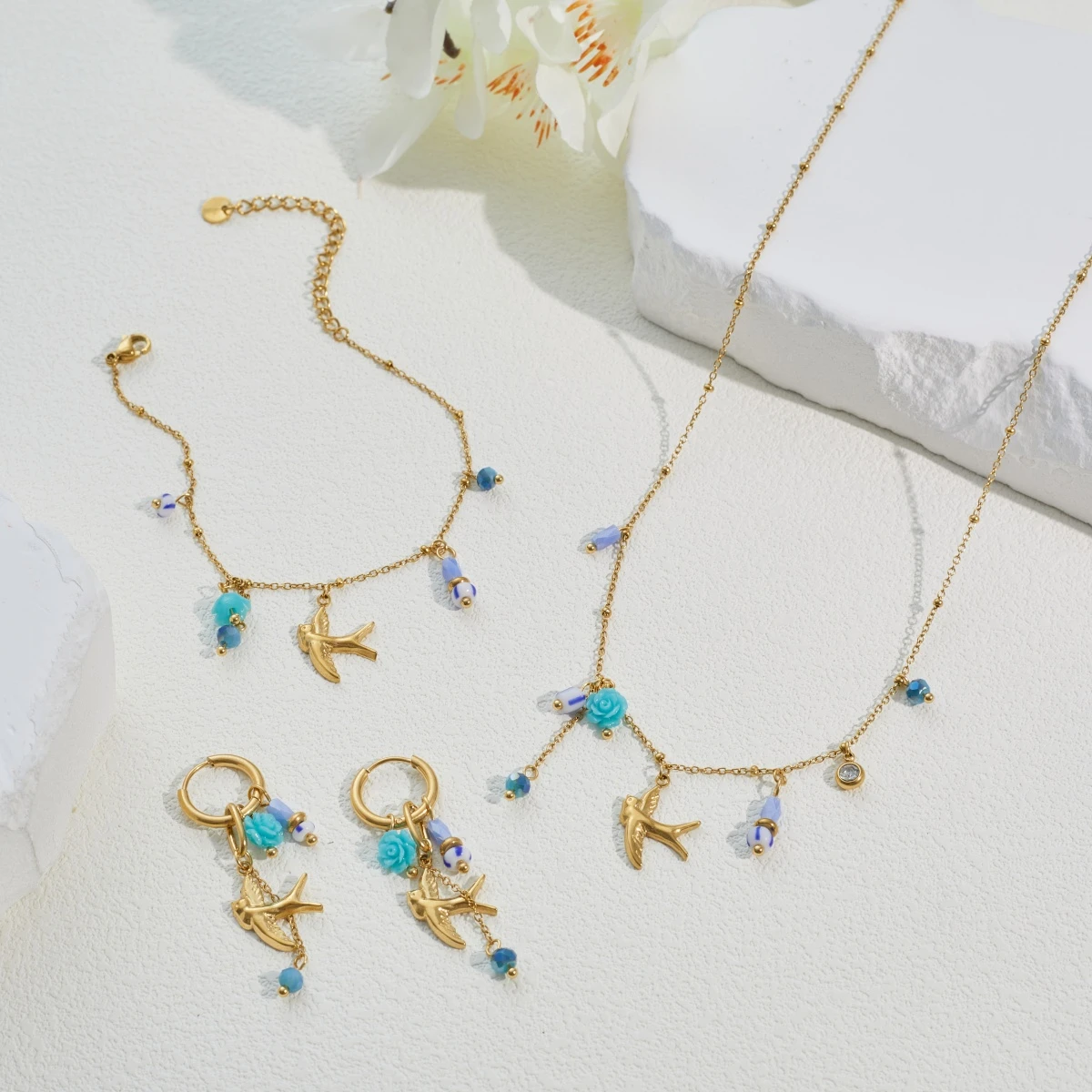 Gouden oorbellen met zwaluw bedel en blauwe kralen - detailweergave